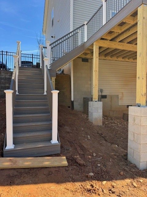 Outdoor stairs and elevated deck attached to a house. Wooden steps and railing on the staircase, and support beams under the deck.