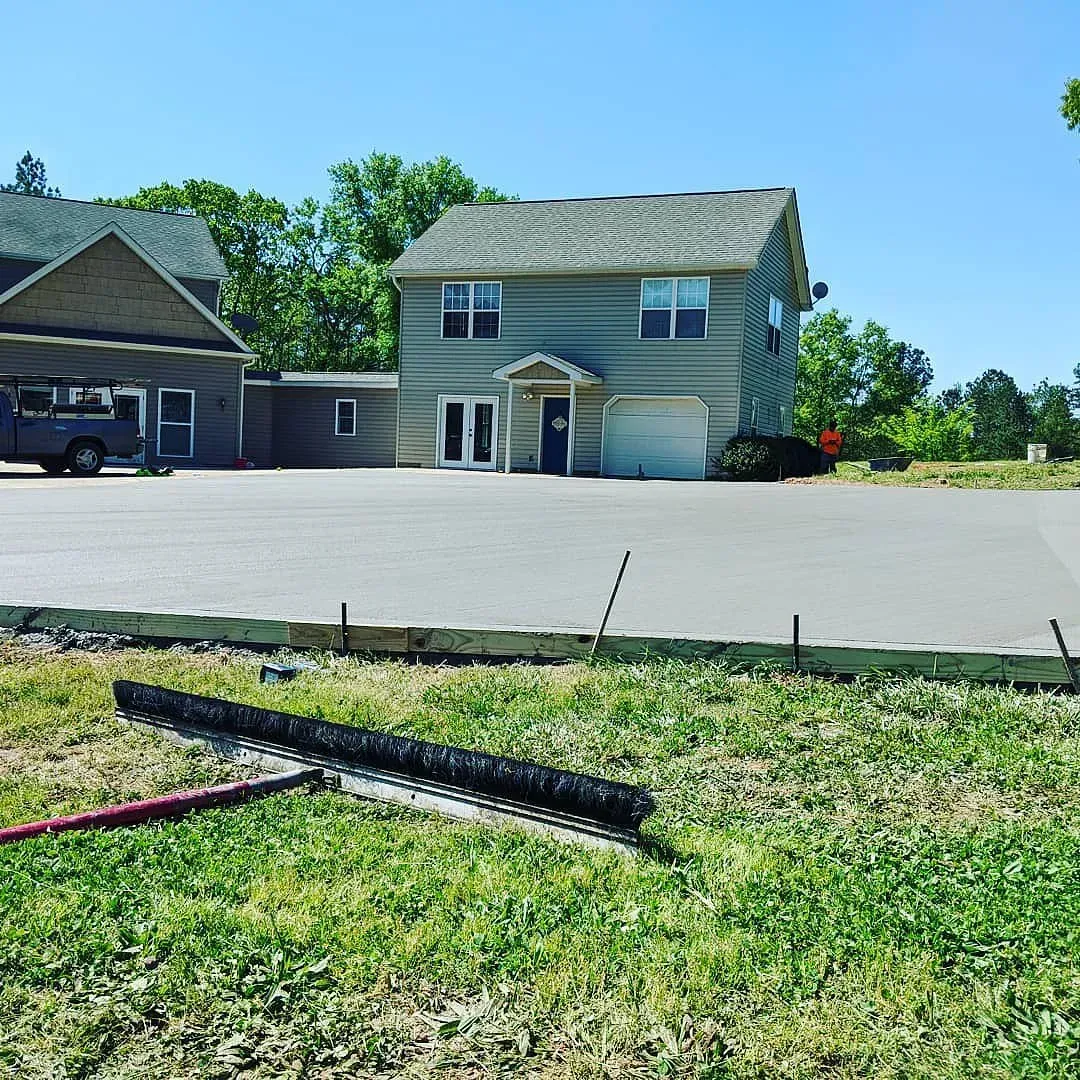 A house with new concrete driveway under construction on a sunny day.