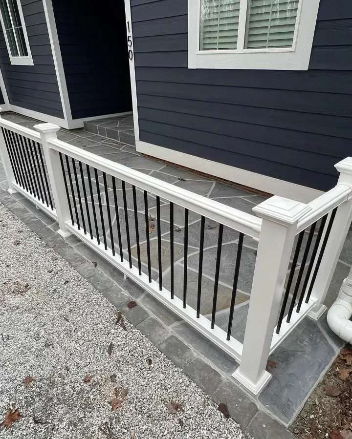 White railing with black vertical bars, in front of a blue house with white trim.