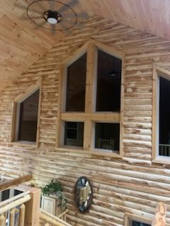 A log cabin with a lot of windows and a ceiling fan