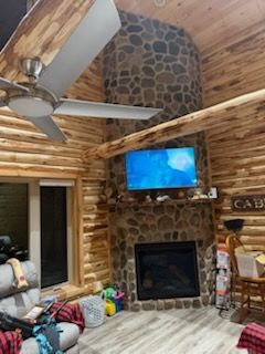A living room in a log cabin with a fireplace and a flat screen TV