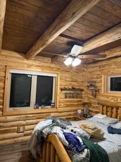 A bedroom in a log cabin with a bed and a ceiling fan