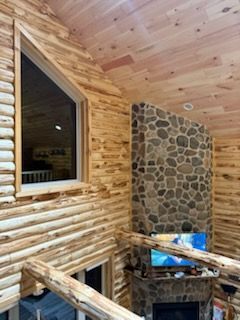 A log cabin with a stone fireplace and a large window