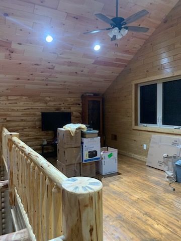 A wooden room with a ceiling fan and boxes on the floor