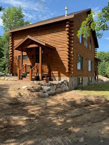 A large log cabin on top of a dirt hill