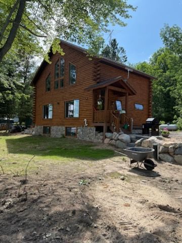 A log cabin with a wheelbarrow in front of it
