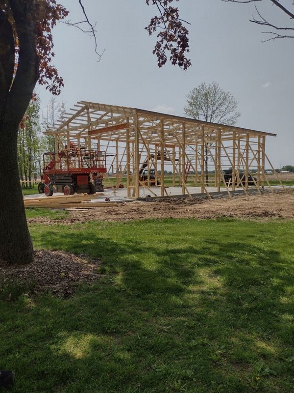 A large wooden structure is being built in a grassy field