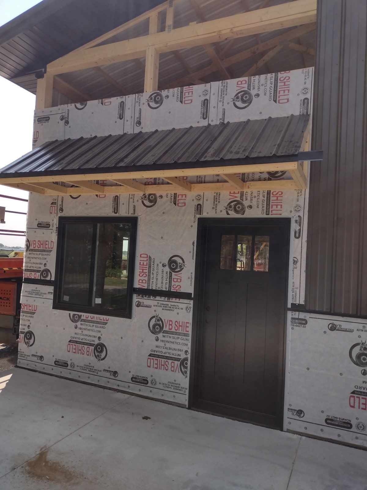 A shed under construction with a black door and windows