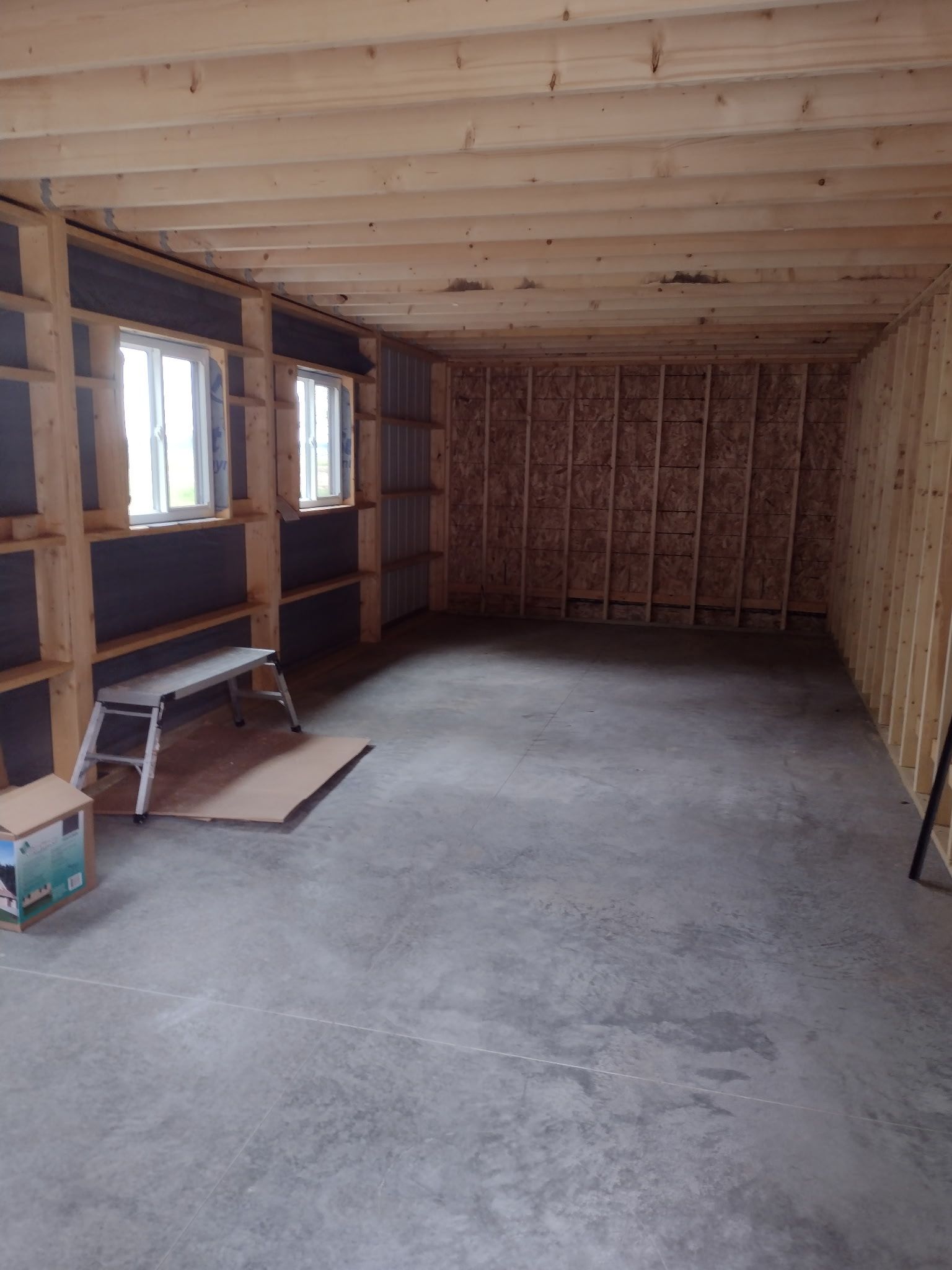 A large empty shed with a concrete floor and wooden walls