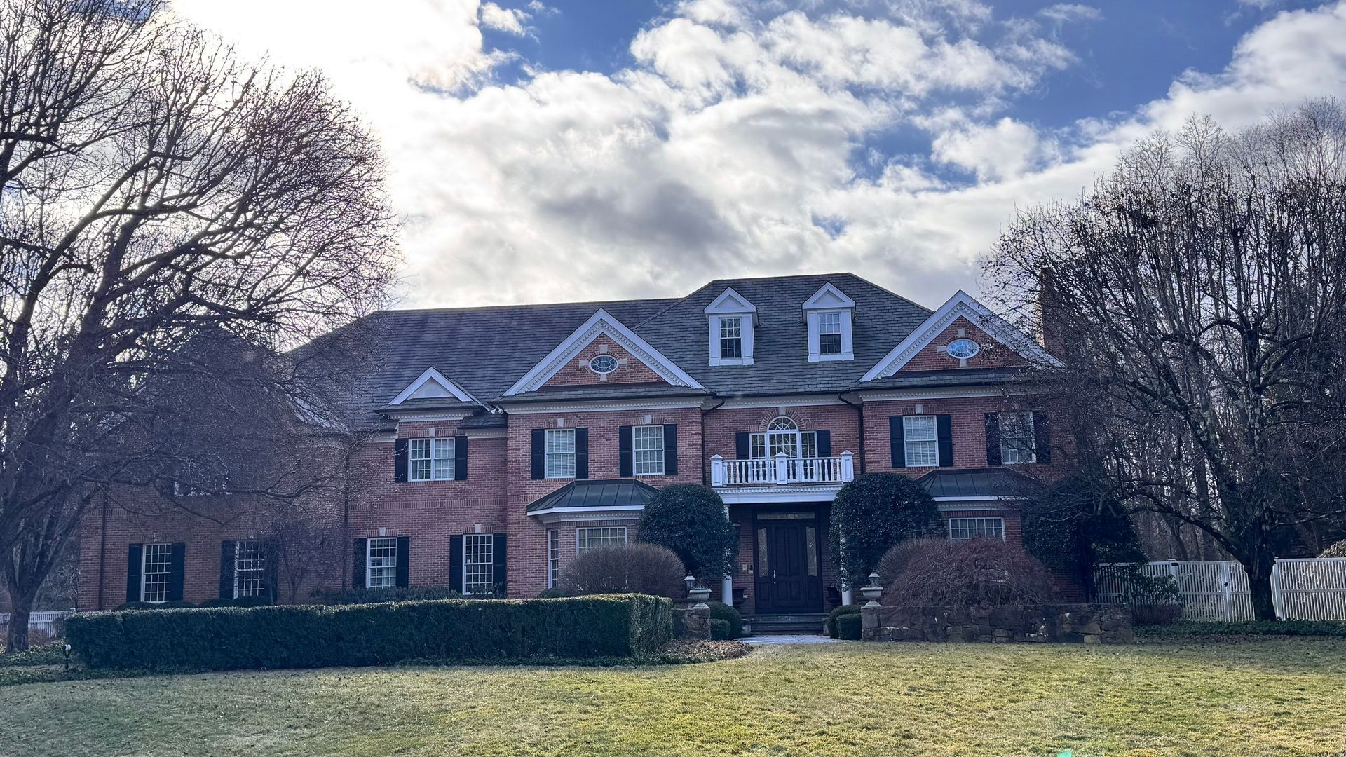 A large brick house with a lush green lawn in front of it