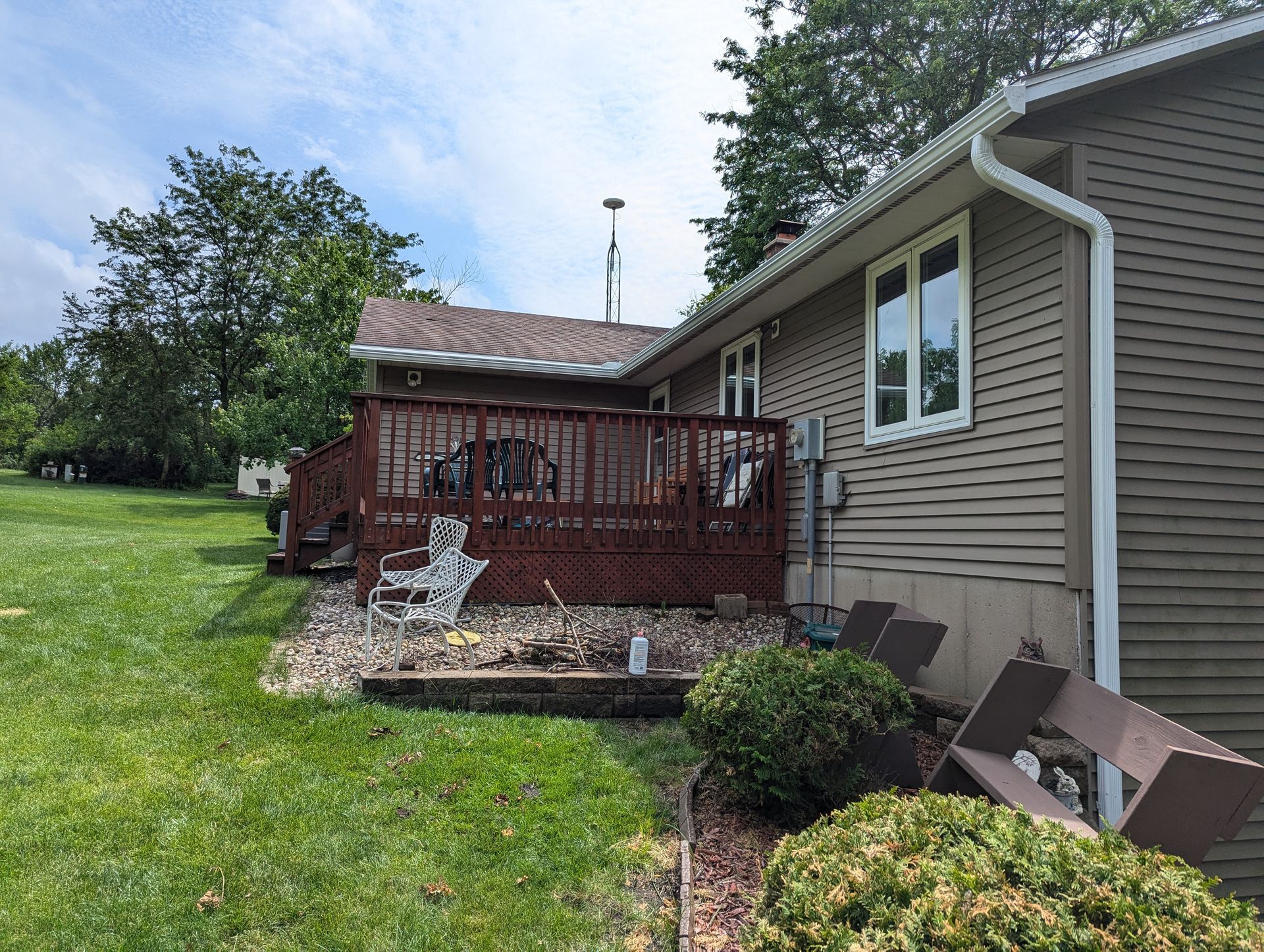 A house with a red deck, brown siding, and a grassy yard.