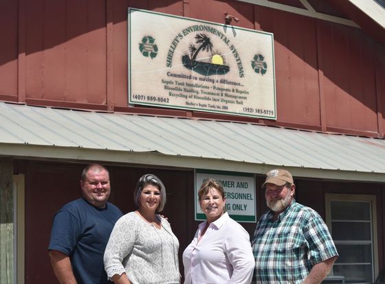 A group of people standing in front of a building with a sign that says recycling