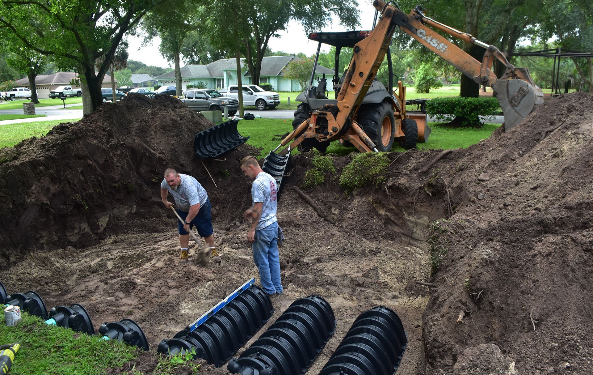 Two men are digging in the dirt next to a tractor.