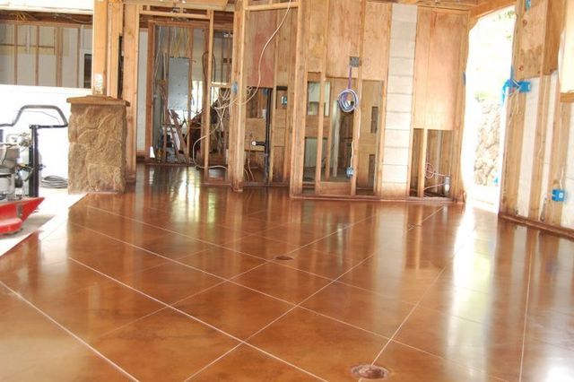 Empty unfinished room with polished wood floor and exposed framing, sunlight streaming through openings