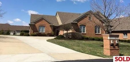 A large brick house with a sold sign in front of it.