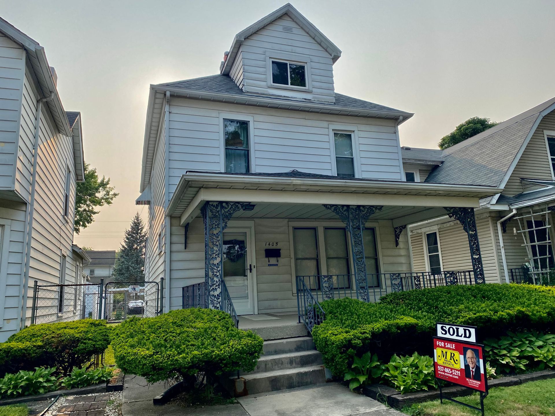 A white house with a sold sign in front of it.