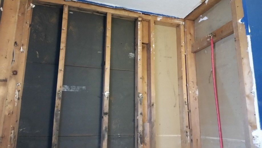 Interior wall framing with exposed studs, insulation, and wiring during renovation