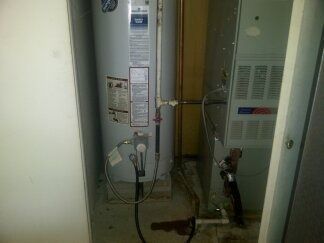 Closet with a water heater, pipes, and utility equipment in a narrow alcove.
