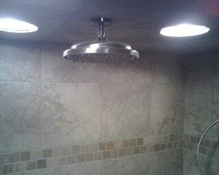 Bathroom shower with stainless steel showerhead and two recessed ceiling lights