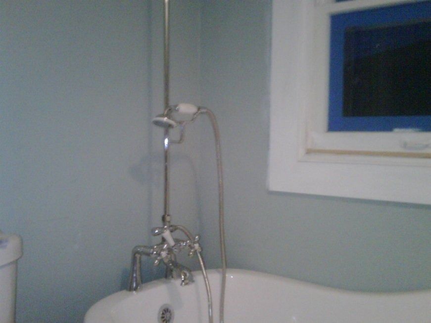 Bathroom with a white tub, chrome showerhead, and blue-trimmed window above it