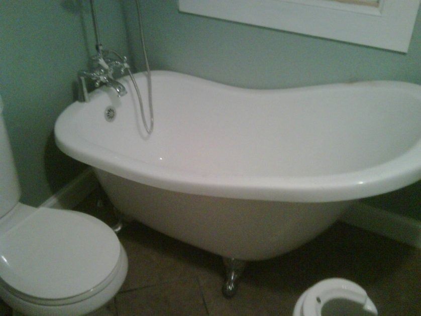 Small bathroom with a white clawfoot bathtub and toilet against a light green wall.