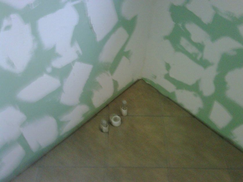 Corner of a room with green-and-white painted walls and three small objects on the floor.