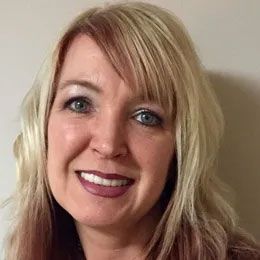Smiling blonde woman with shoulder-length hair against a plain background
