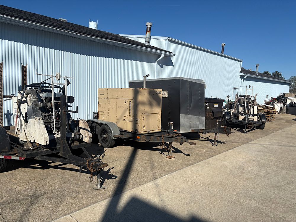 Equipment trailers lined up beside a blue metal building on a sunny industrial lot