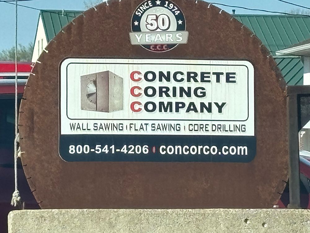 Concrete Coring Company sign with logo, services, phone number, and website on a brown display board