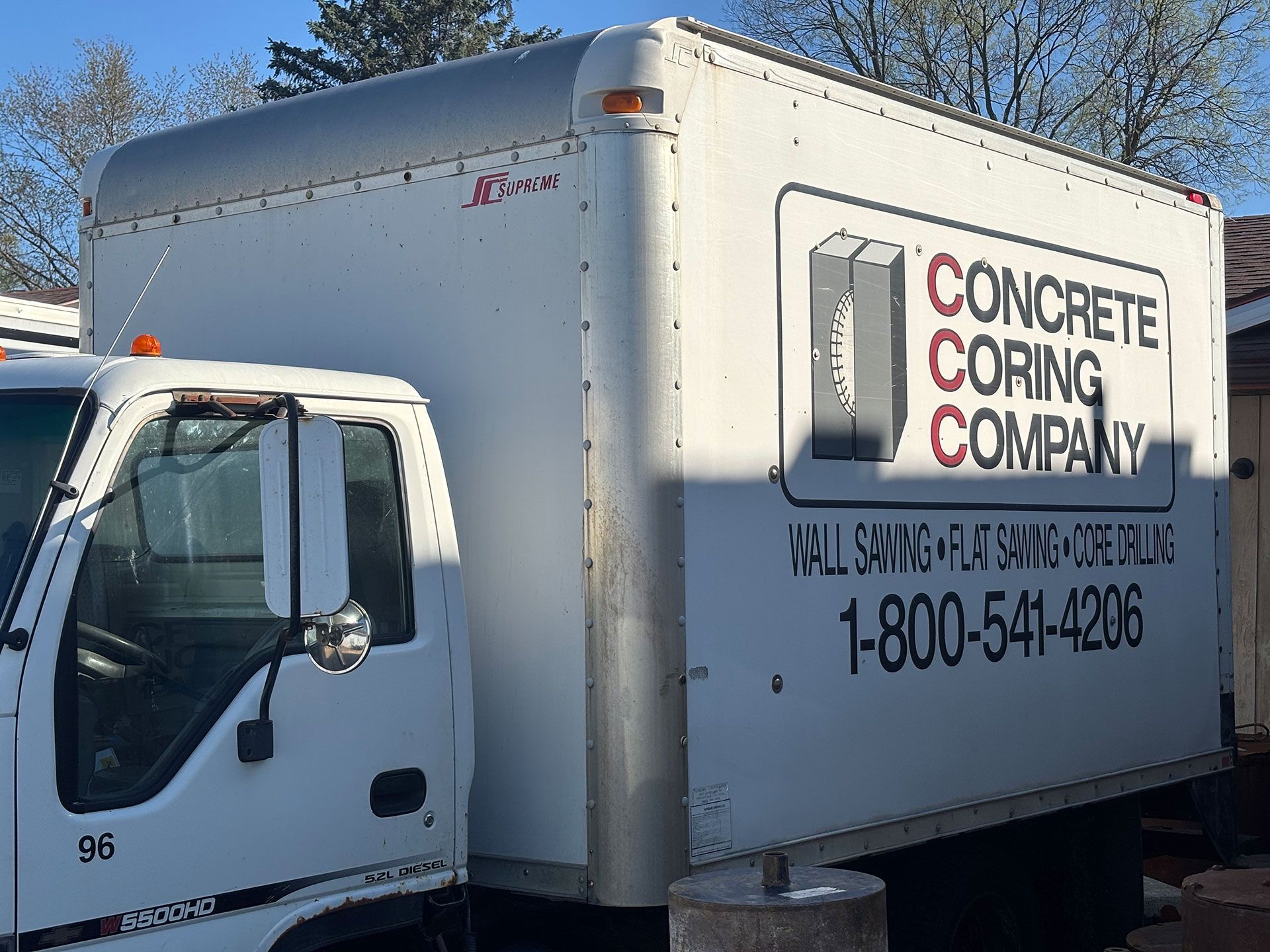 White Concrete Coring Company box truck with logo and phone number parked outdoors