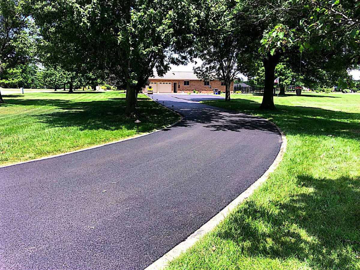 A driveway that leads to a house surrounded by trees and grass