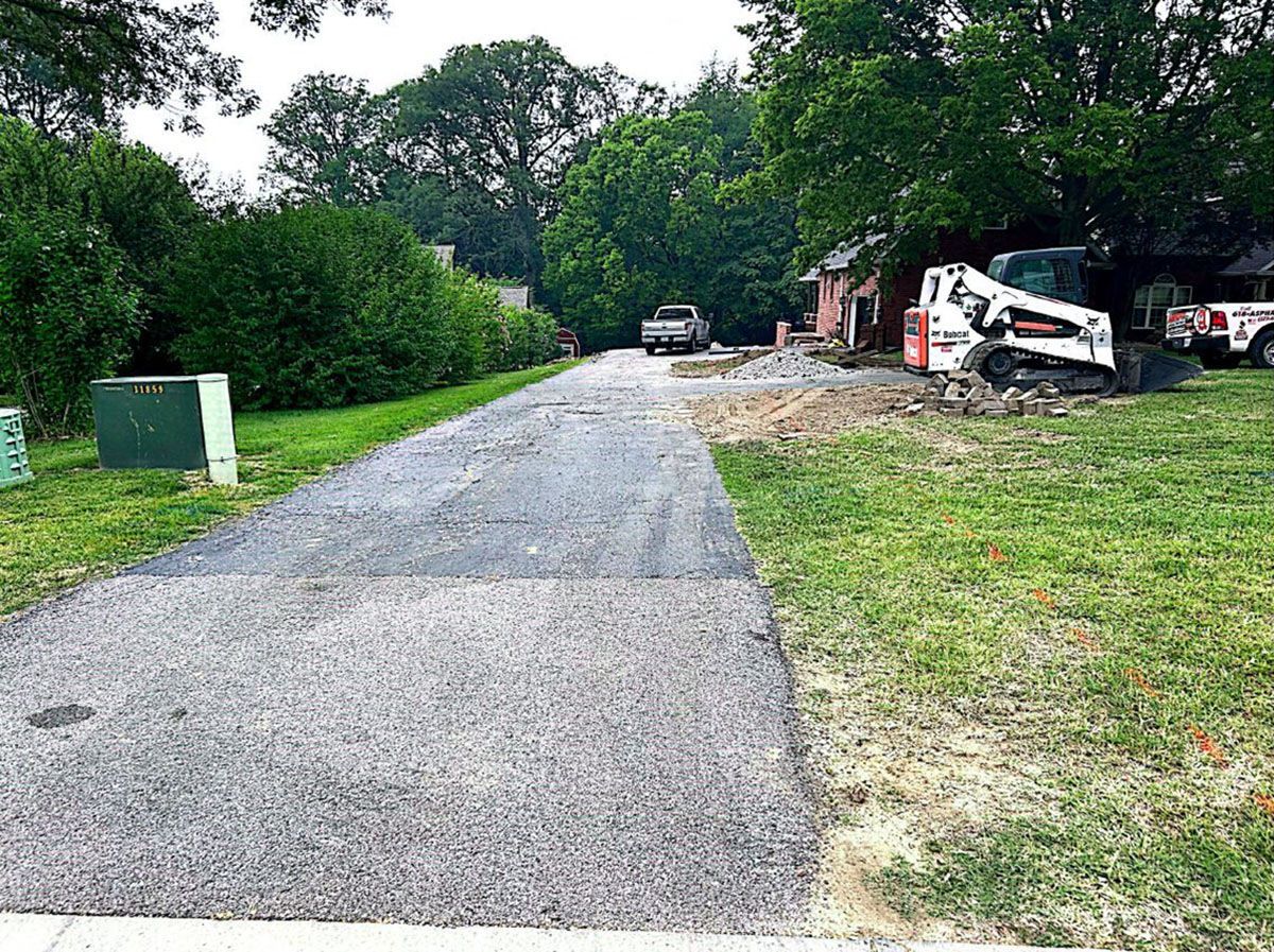 A bobcat is parked on the side of a road next to a house