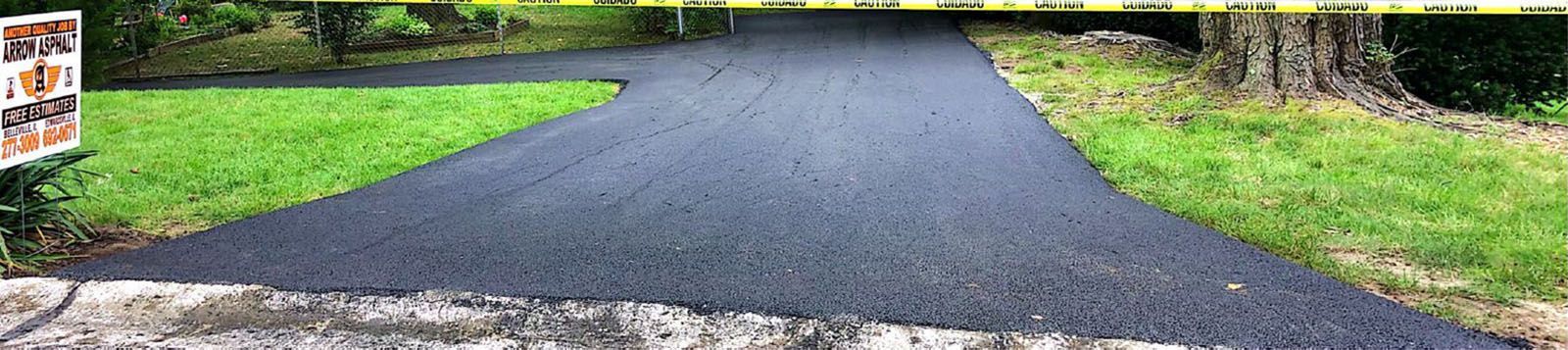 A black asphalt road going through a lush green field
