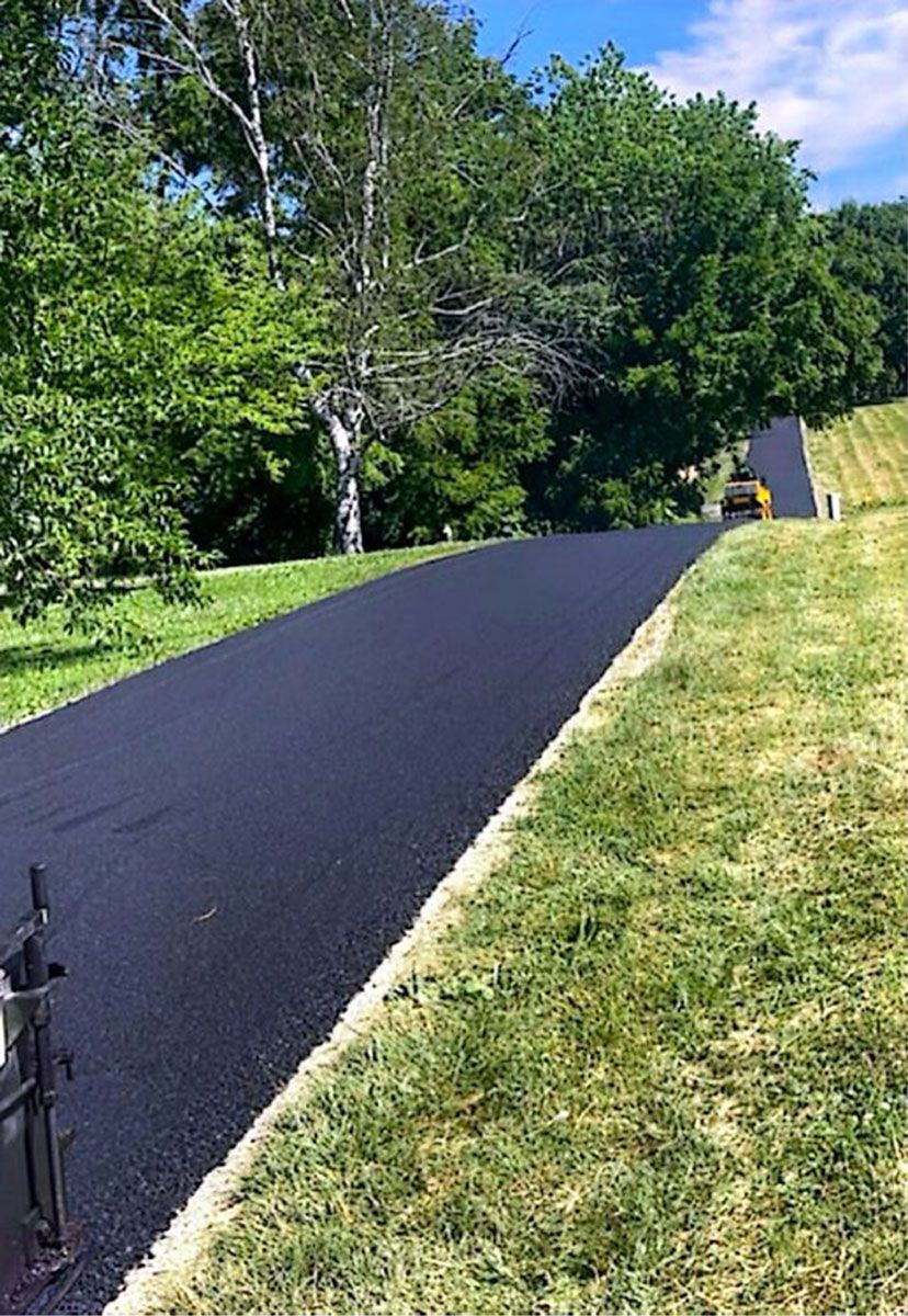 A black asphalt road going through a grassy field