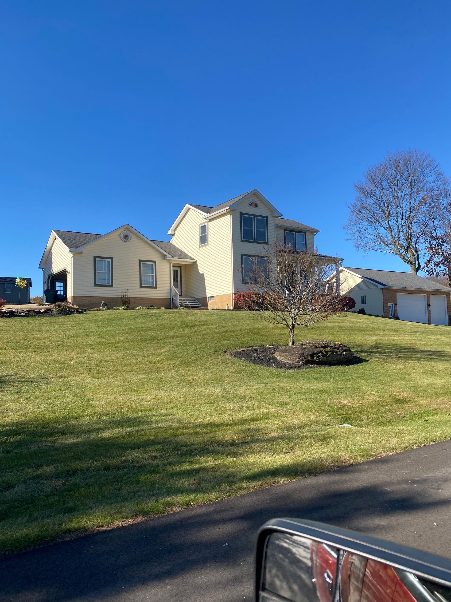 A large white house is sitting on top of a lush green hill.