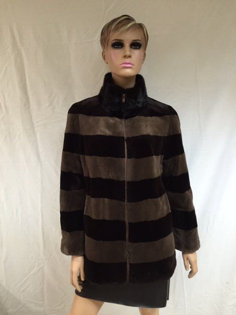 Mannequin wearing a brown and black striped fur coat with a high collar, standing in front of a white backdrop.