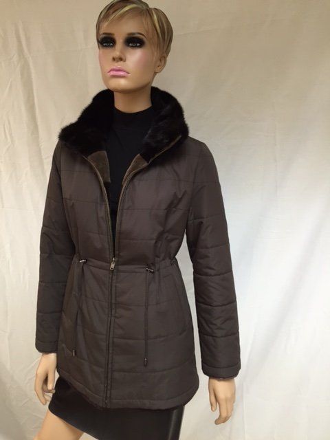 Mannequin in a brown quilted jacket with fur collar. Black turtleneck, dark skirt. Indoor setting.