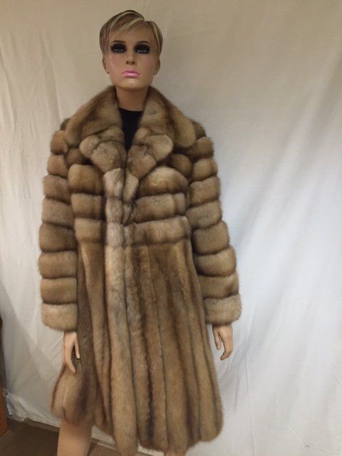 Mannequin wearing a long, brown fur coat with a notched collar.