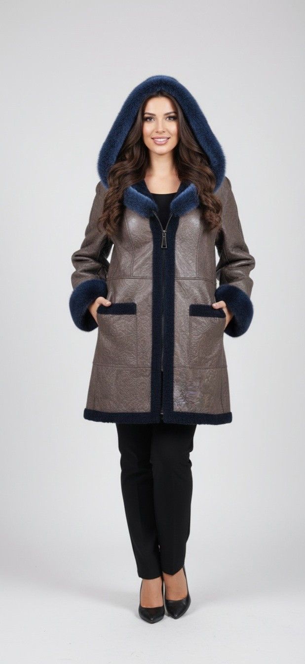 Woman wearing a brown and blue hooded coat, standing in front of a white background.