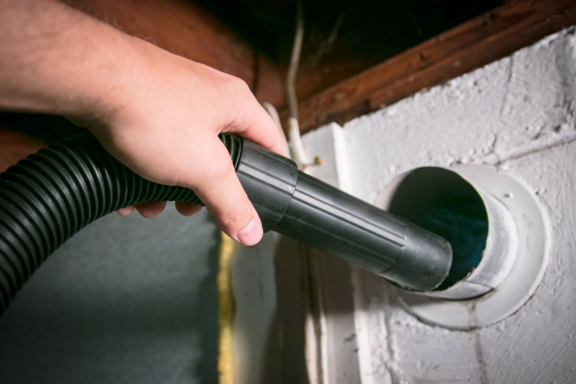 A person is using a vacuum cleaner to clean a hole in a wall