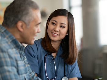 A nurse is talking to an older man in a hospital room.