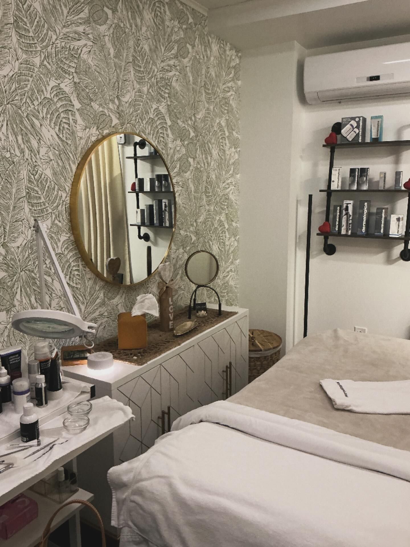 Spa room with treatment bed, skincare products, and wallpaper.