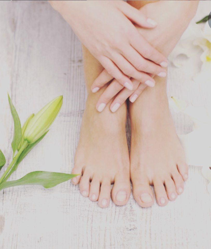 Bare feet crossed with hands resting on top, white flowers.