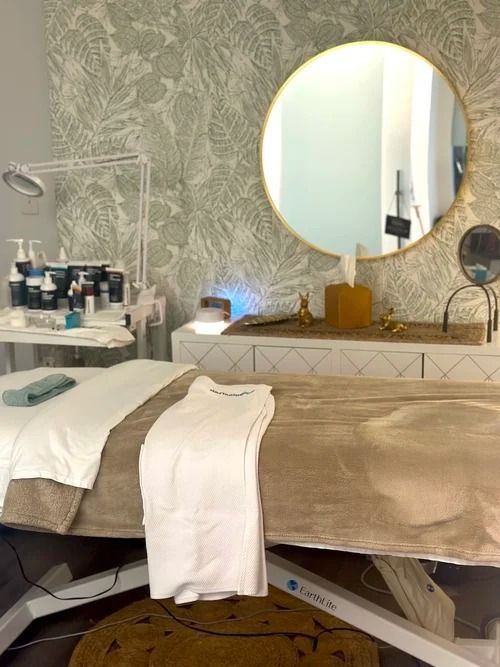 Spa treatment room with a massage table, products, and a mirror.