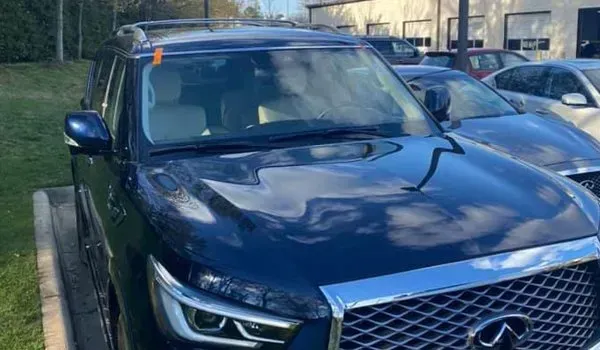 Blue Infiniti QX80 SUV parked outdoors with a shiny hood and chrome grill.
