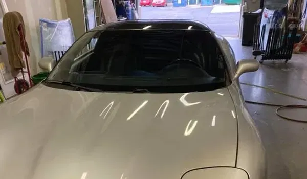 Silver Corvette sports car in a garage with a black top.