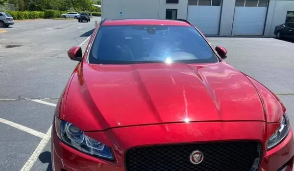 Red Jaguar SUV parked in a lot on a sunny day.