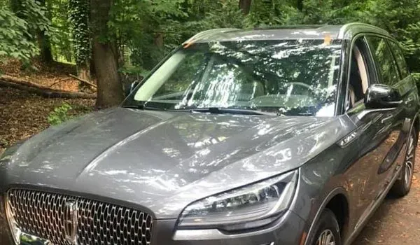 Gray Lincoln Corsair SUV parked on a wooded path with trees in the background.