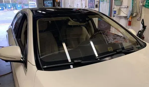 White car with a black roof, windshield wipers up, interior visible.