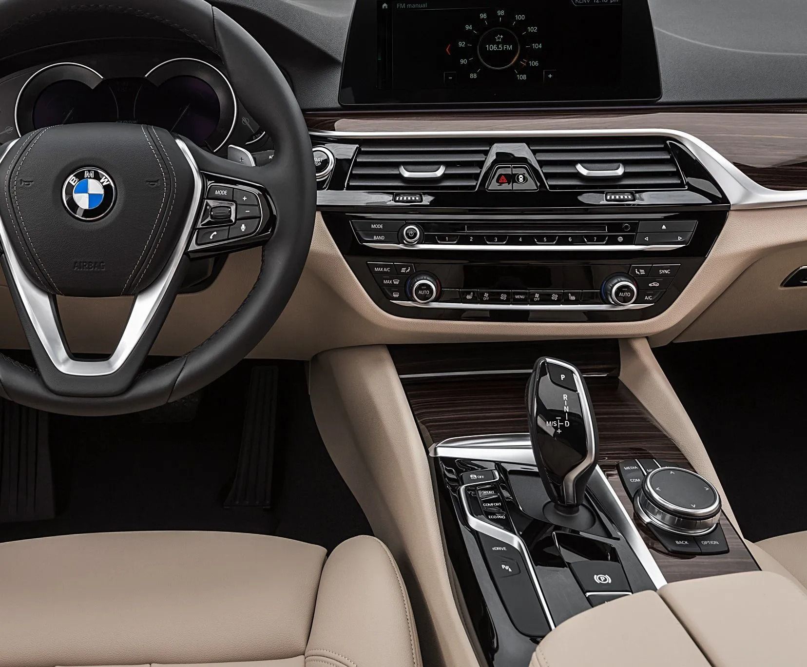 Interior of a tan and black BMW car showing the dashboard, steering wheel, and center console.
